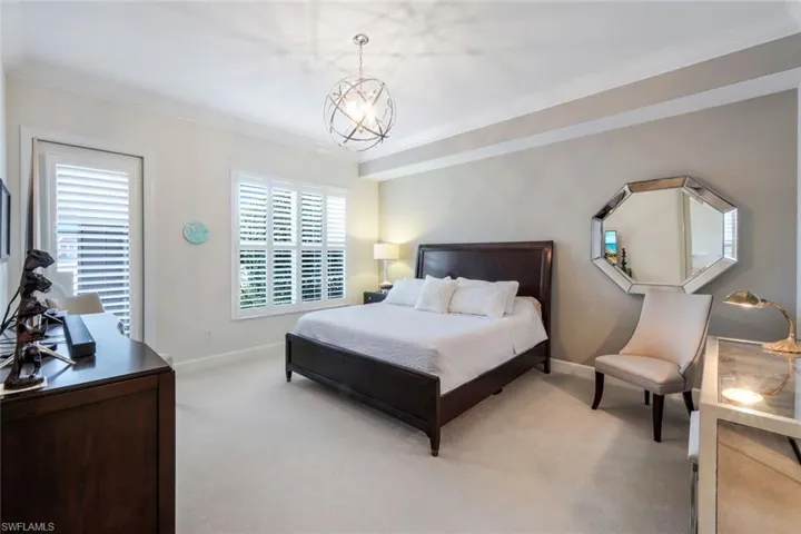 Bedroom with crown molding, light colored carpet, and a chandelier