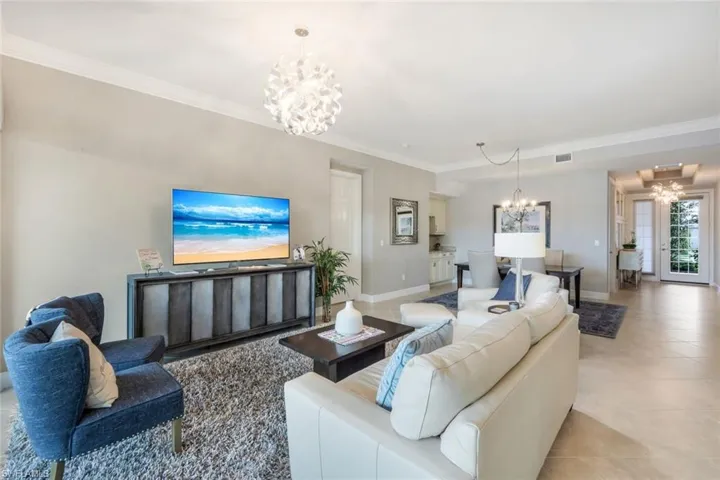 Living room featuring a chandelier, crown molding, and light tile patterned floors