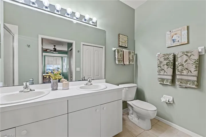 Bathroom featuring toilet, vanity, tile patterned floors, and ceiling fan