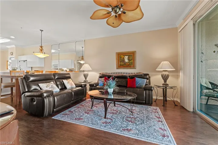 Living room with dark hardwood / wood-style floors, ceiling fan, and ornamental molding