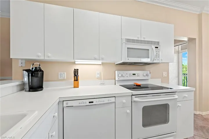 Kitchen featuring white cabinets, white appliances, crown molding, and light tile patterned floors