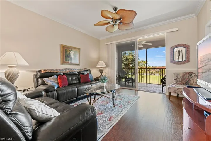 Living room with ceiling fan, dark hardwood / wood-style flooring, and crown molding