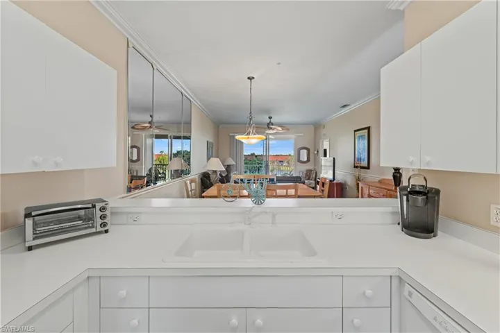 Kitchen with pendant lighting, white cabinets, white dishwasher, ornamental molding, and kitchen peninsula