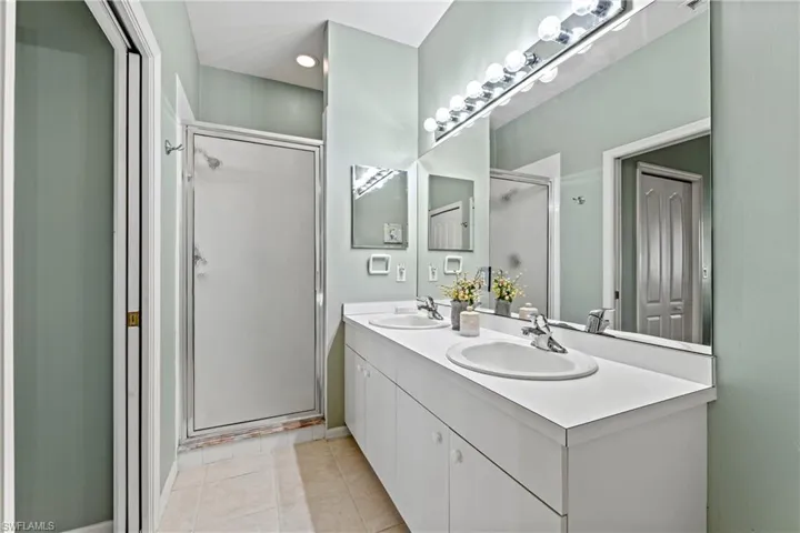 Bathroom with tile patterned flooring, vanity, and an enclosed shower