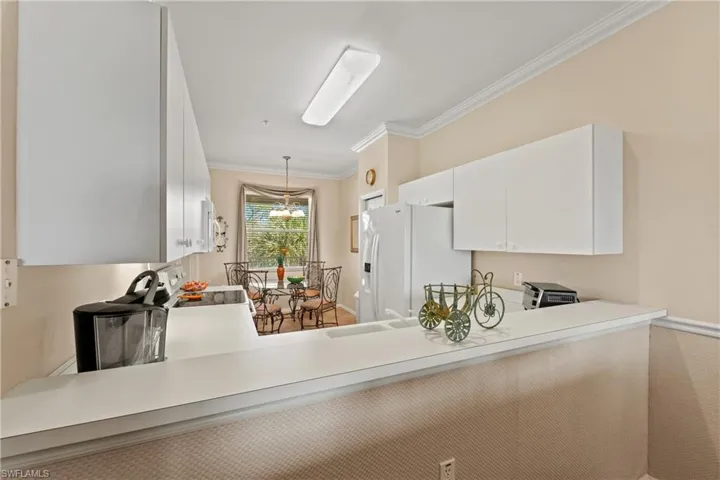 Kitchen with sink, pendant lighting, white appliances, white cabinets, and ornamental molding
