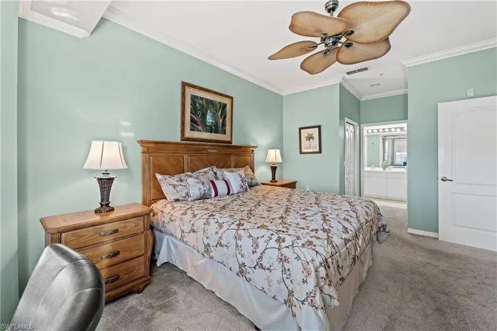 Bedroom with carpet, ceiling fan, ornamental molding, and ensuite bath