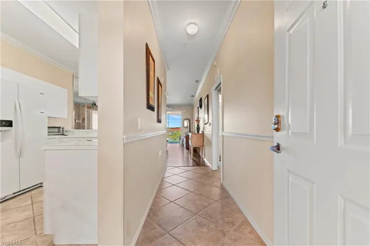 Hallway with light tile patterned floors and ornamental molding