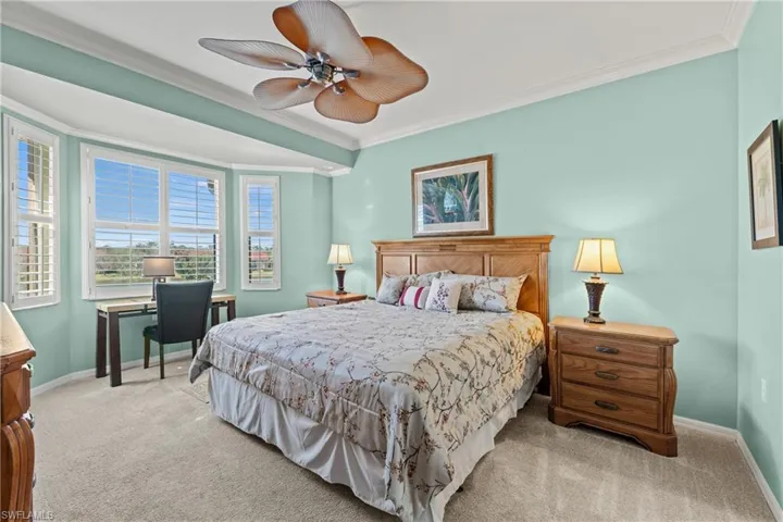 Carpeted bedroom with ceiling fan and ornamental molding