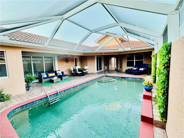 View of pool with outdoor lounge area, a patio area, and glass enclosure