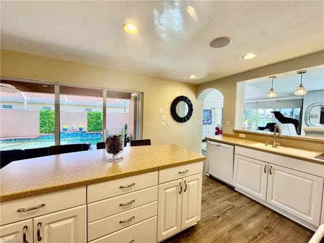 Kitchen with sink, hardwood / wood-style flooring, dishwasher, white cabinetry, and hanging light fixtures