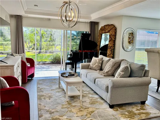 Living room featuring crown molding, a notable chandelier, and hardwood / wood-style flooring