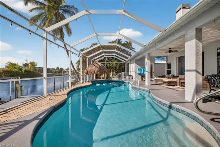 Swimming pool featuring a patio area, a sunroom, glass enclosure, and a ceiling fan