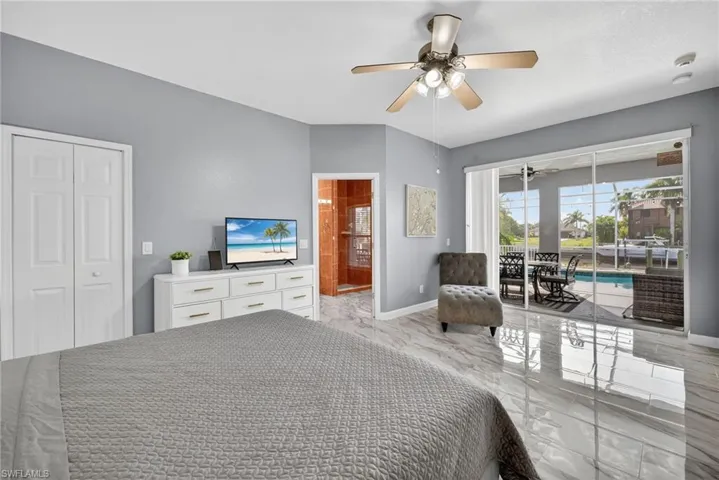 Bedroom featuring access to exterior, ceiling fan, ensuite bathroom, a sunroom, and light marble finish floors