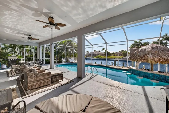 Swimming pool with a water view, a lanai, an outdoor hangout area, a patio, and a ceiling fan