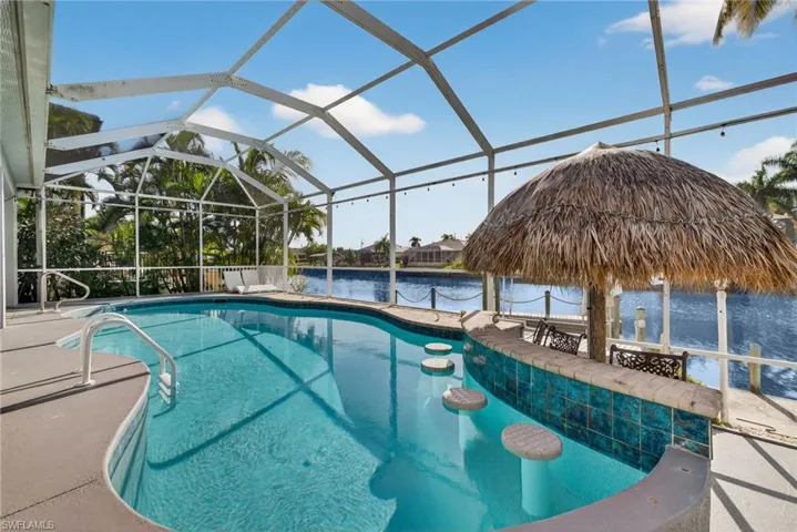 Outdoor pool featuring a water view, a lanai, boat lift, a sunroom, and a dock