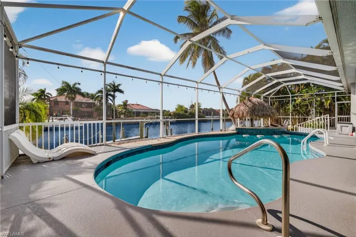 Swimming pool with a sunroom, a water view, and glass enclosure
