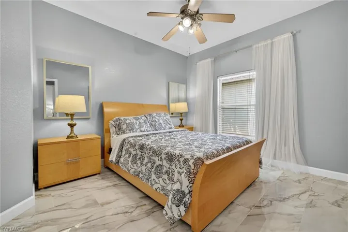 Bedroom featuring a ceiling fan and light marble finish floors