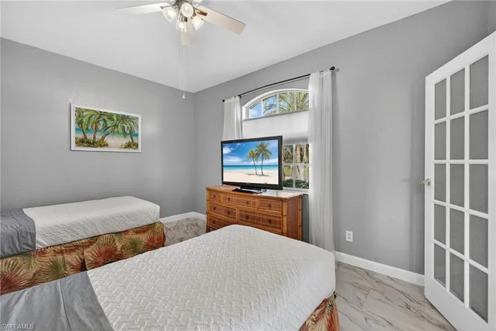 Bedroom with a ceiling fan and light marble finish floors