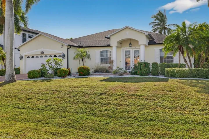 Single story home featuring french doors, stucco siding, a front lawn, and a garage