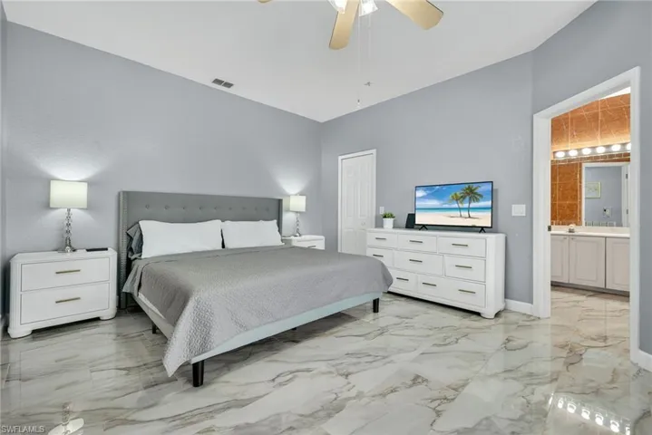 Bedroom featuring light marble finish flooring, a ceiling fan, and a closet