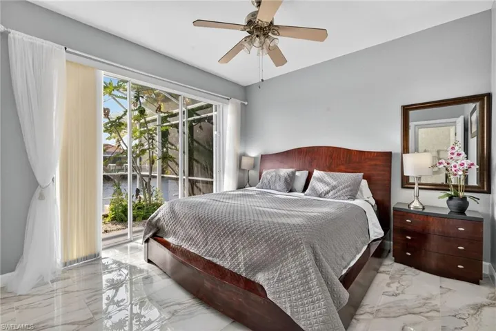 Bedroom featuring light marble finish floors, access to outside, ceiling fan, and a water view