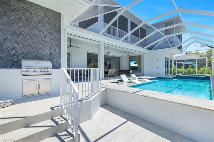 View of pool featuring ceiling fan, area for grilling, a patio, an outdoor kitchen, and glass enclosure
