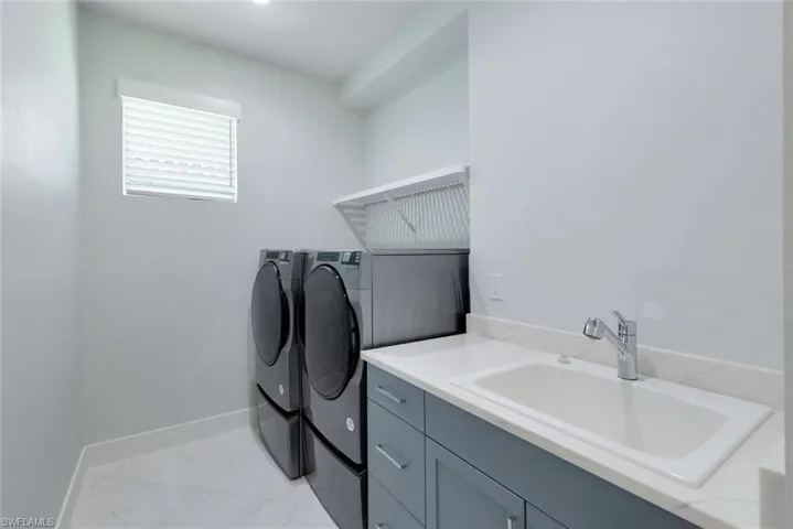 Laundry area featuring sink, light tile flooring, and independent washer and dryer
