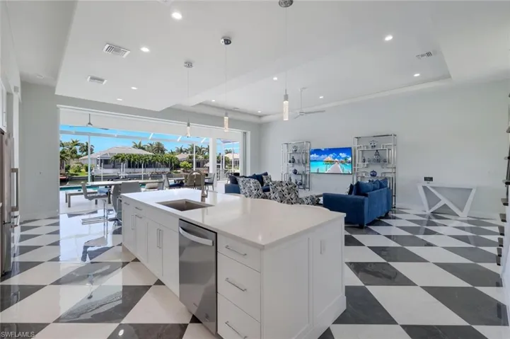 Kitchen with a healthy amount of sunlight, white cabinets, and a kitchen island with sink