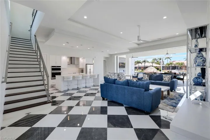 Living room featuring a tray ceiling, ceiling fan, and light tile floors