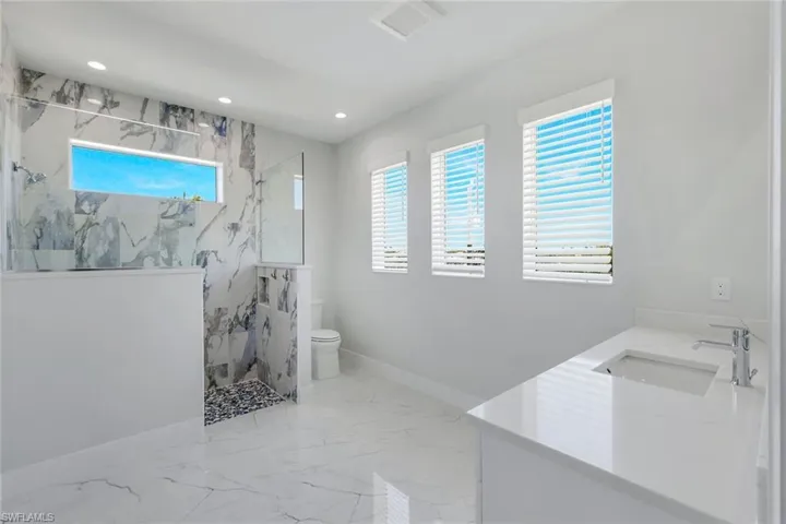 Bathroom featuring tile floors, a tile shower, toilet, and vanity