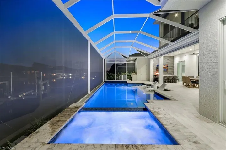 Pool at night featuring a lanai and a patio area