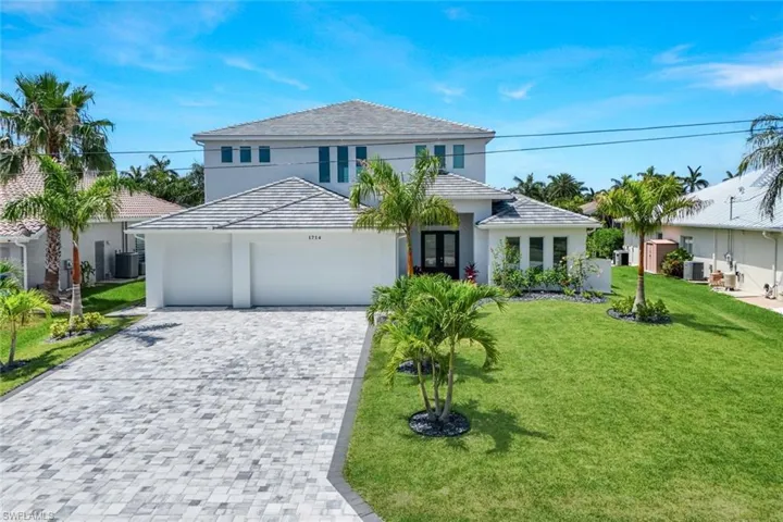 View of front of property featuring central AC, a front lawn, and a garage