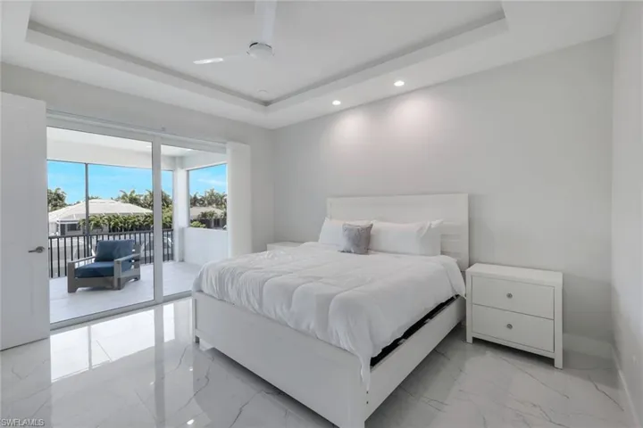Tiled bedroom featuring ceiling fan, a raised ceiling, and access to outside