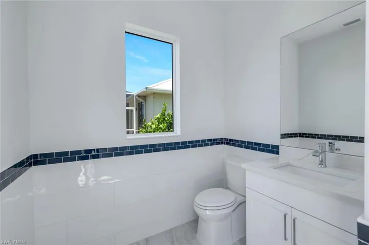 Bathroom with plenty of natural light, vanity, toilet, and tile walls