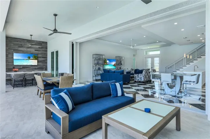 Living room featuring a tray ceiling, french doors, light tile flooring, and ceiling fan