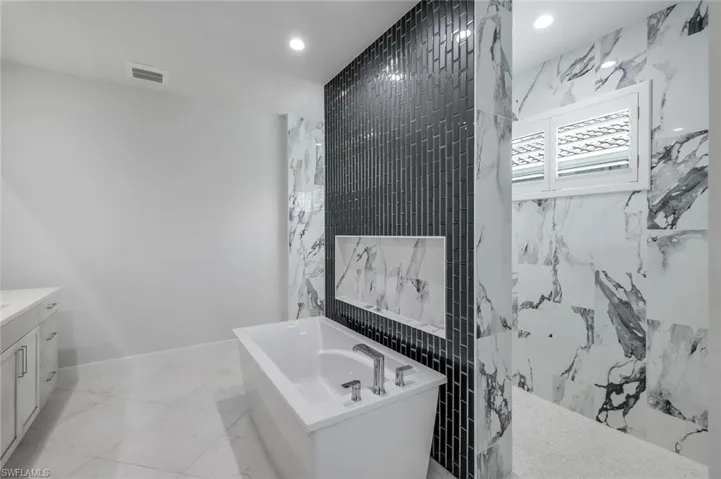 Bathroom with tile floors, vanity, and a bathtub