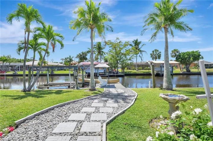 View of dock with boat lift, a residential view, a water view, and a yard