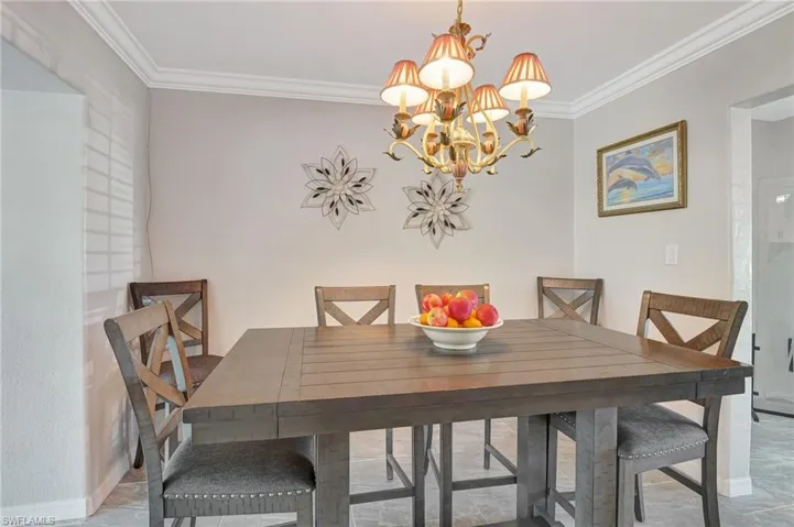 Dining space with ornamental molding and an inviting chandelier