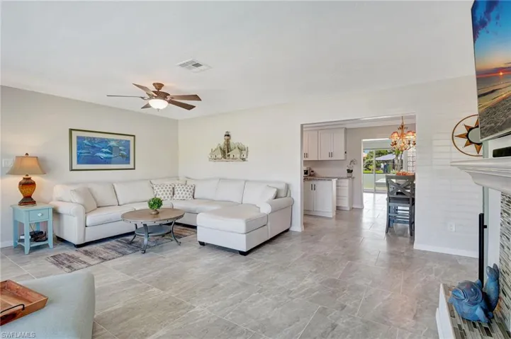 Living room featuring ceiling fan with notable chandelier, baseboards, and visible vents