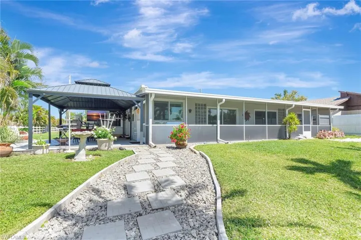 Back of property with a sunroom, metal roof, a gazebo, a standing seam roof, and a lawn