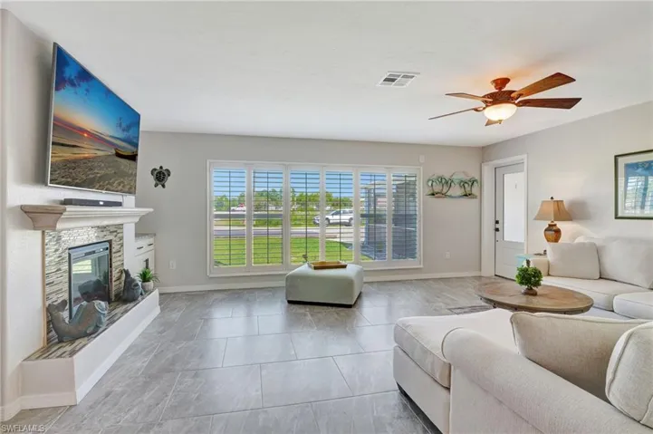 Living room featuring baseboards, visible vents, a fireplace, and a ceiling fan