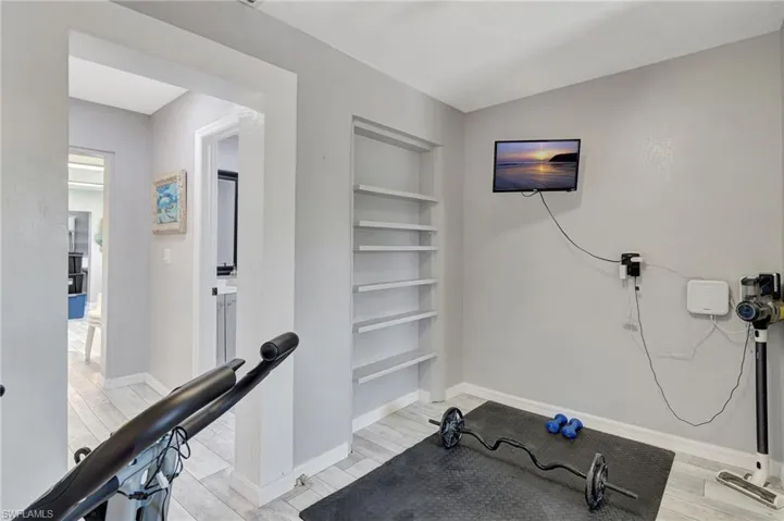 Exercise area featuring baseboards, light wood-style floors, and built in shelves