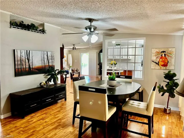 Dining room featuring light wood-type flooring, ceiling fan, crown molding, and a textured ceiling