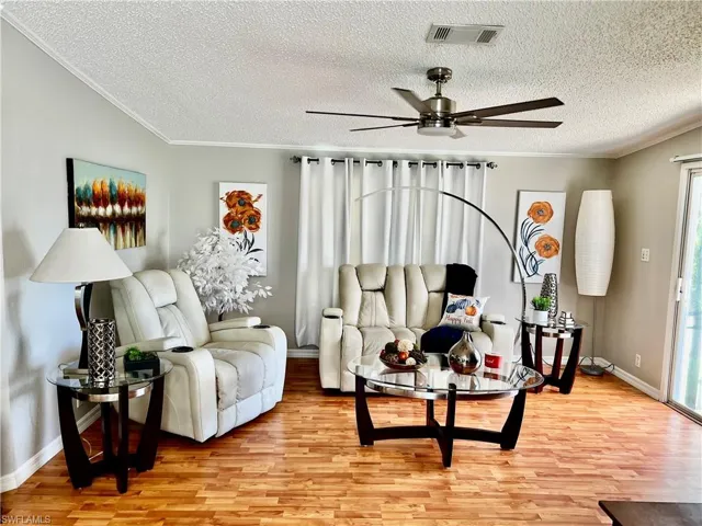 Living area with light wood-style flooring, crown molding, a textured ceiling, and a ceiling fan