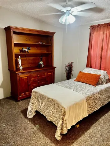 Bedroom with a textured ceiling, and a ceiling fan