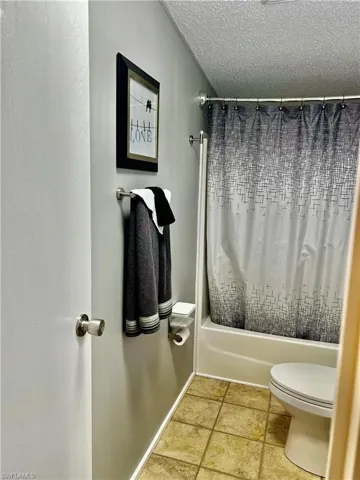 Bathroom featuring shower / bath combo and a textured ceiling