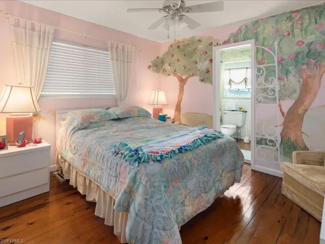 Bedroom featuring connected bathroom, dark wood-type flooring, and ceiling fan