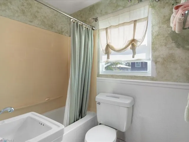 Full bathroom featuring toilet, sink, and shower / bath combo with shower curtain