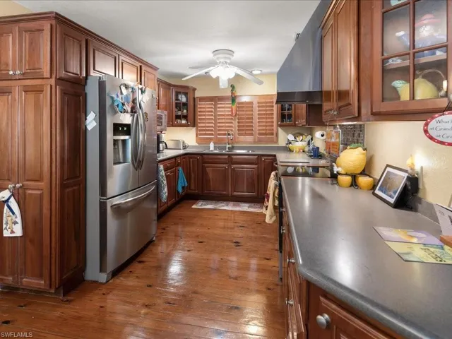 Kitchen with sink, exhaust hood, ceiling fan, stainless steel refrigerator with ice dispenser, and dark wood-type flooring