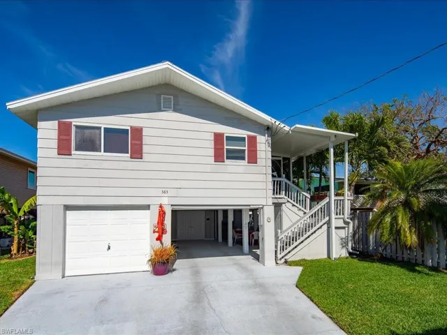View of front of property with a carport, a garage, and a front lawn